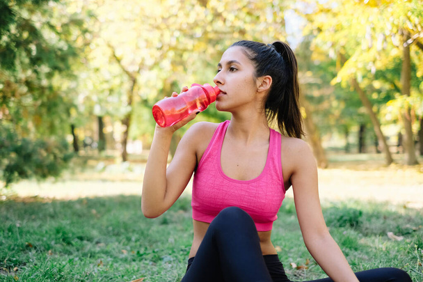 Jonge sportieve vrouw neemt energy drink na lange training - Foto, afbeelding