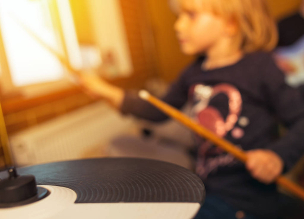blurry image of drum and wooden drumsticks in hands. Girl learning and play drum set in music room, the concept of musical instrument. - 写真・画像