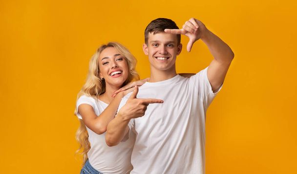 Cheerful millennial couple taking picture with imaginary camera - Photo, Image