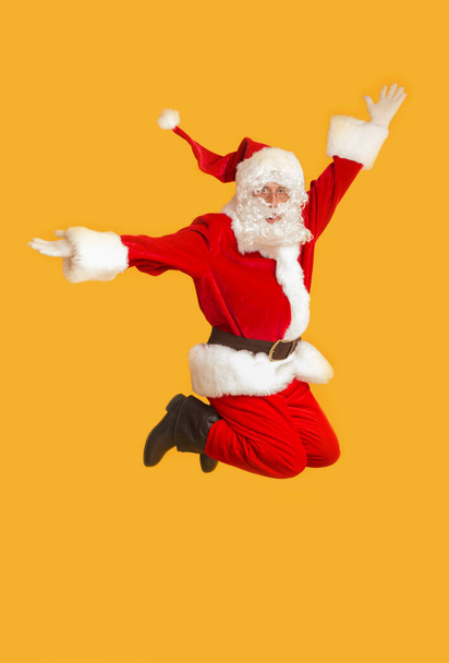 Turuncu arka planda zıplayan Mutlu Noel Baba - Fotoğraf, Görsel