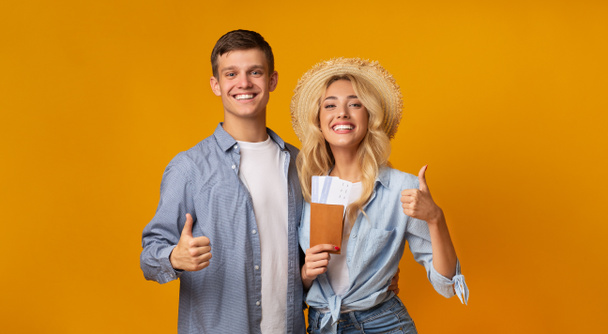 Cheerful couple holding passports with tickets and showing thumbs up - Foto, immagini