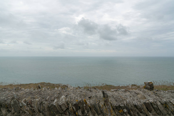 alte Steinmauer und Blick über einen ausgedehnten Ozean unter einem bewölkten Himmel - Foto, Bild
