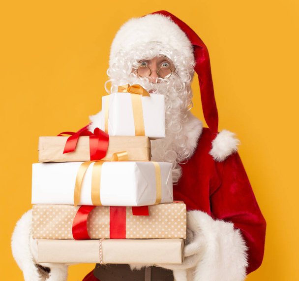 Santa drží dárkové krabice pro děti na oranžové - Fotografie, Obrázek
