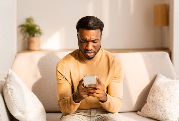Distended Man Holding Smaprtphone Czytanie wiadomości Siedząc na kanapie w domu - Zdjęcie, obraz