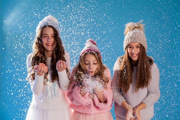 Τρία μοντέρνα όμορφα κορίτσια το χειμώνα καπέλα παίζουν με το χιόνι - Φωτογραφία, εικόνα