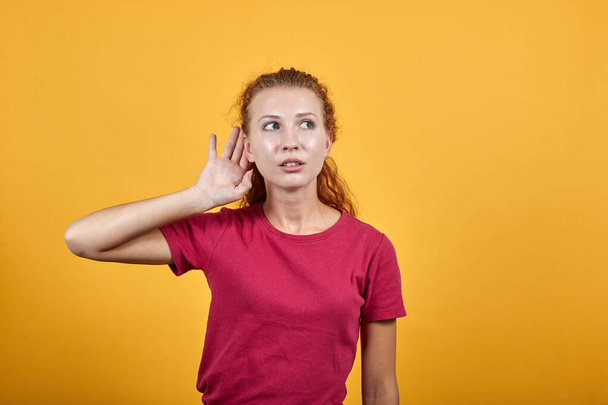 Jeune femme européenne à l'écoute de quelque chose en mettant la main sur l'oreille
. - Photo, image