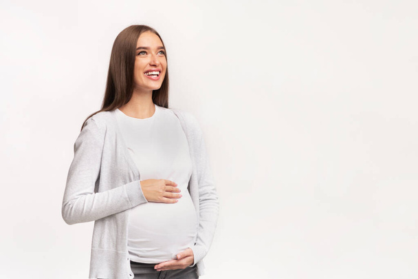 Счастливая беременная леди, трогающая живот стоя, студия Shot
 - Фото, изображение