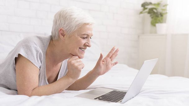 Cheerful grandmother talking with relatives via digital tablet online - Fotografie, Obrázek