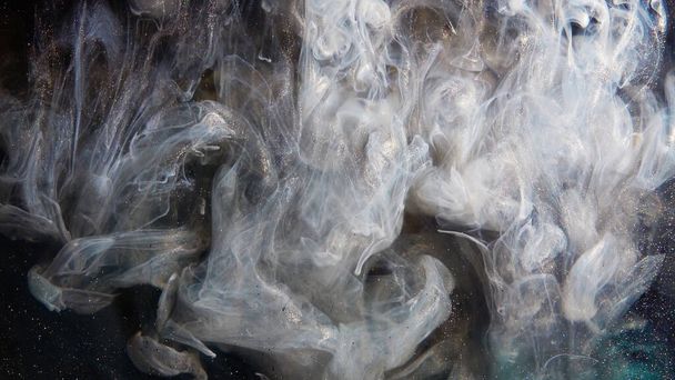 Abstract bronze paint mixed with different multi-colored paints in water in slow motion. Inky cloud swirling flowing underwater. Abstract smoke explosion - Photo, Image
