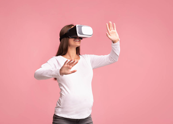 Ενθουσιασμένη έγκυος γυναίκα χρησιμοποιώντας εικονικά ακουστικά πραγματικότητα στέκεται, Studio Shot - Φωτογραφία, εικόνα