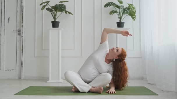 Young pregnant woman doing stretching and fitness in living room at home - Filmmaterial, Video