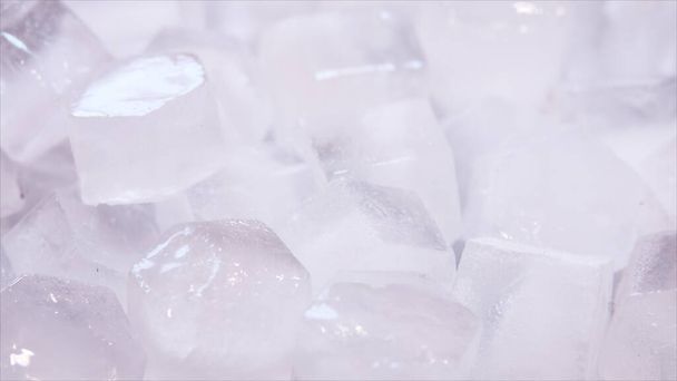 Макро-кадры кубиков льда из чистой воды, которые тают в замедленной съемке на белом фоне. Концепция: чистая горная родниковая вода, лед, коктейли, свежие и замороженные продукты
. - Фото, изображение