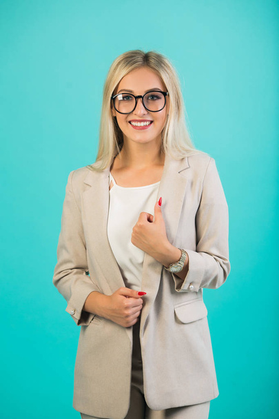 beautiful young woman in suit with glasses on a blue background - Фото, зображення