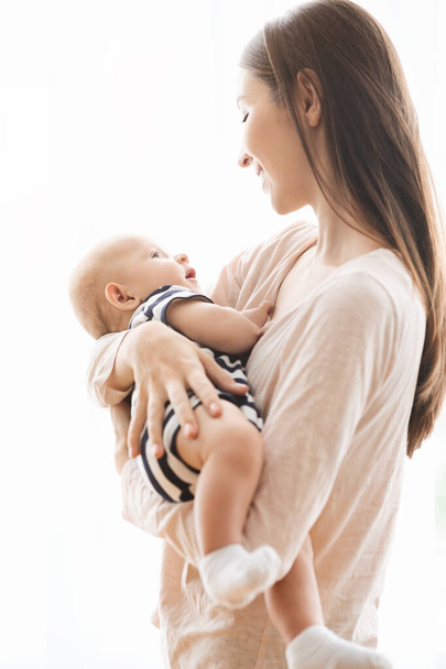 Retrato de bela mãe lulling seu bebê nos braços
 - Foto, Imagem