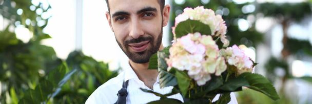 Hombre barbudo jardinero sosteniendo flor blanca en maceta
 - Foto, Imagen