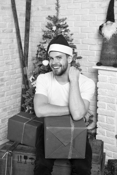 delivery christmas gifts. The morning before Xmas. man in santa hat hold christmas present. happy santa man. online christmas shopping. New year scene with tree and gifts. Merry Christmas. Happiness - Foto, Imagen