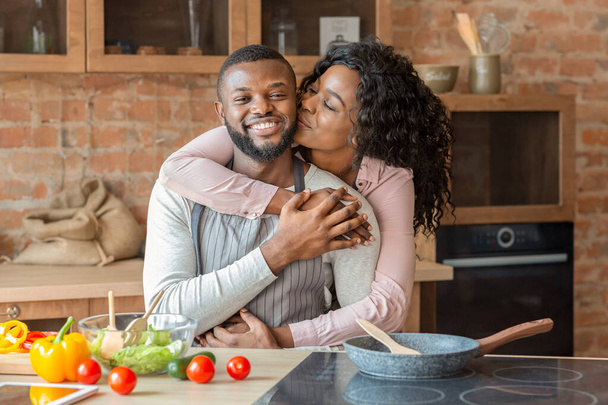 Retrato de una encantadora pareja negra abrazándose en la cocina
 - Foto, Imagen