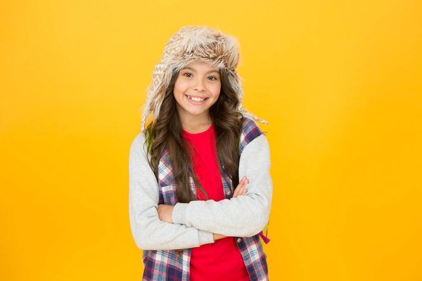 Keep little head warm and fashionable. Happy child with fashionable winter look on yellow background. Small girl smiling in fashionable fur hat. Fashionable and ideal for cold weather adventures - Foto, Imagem