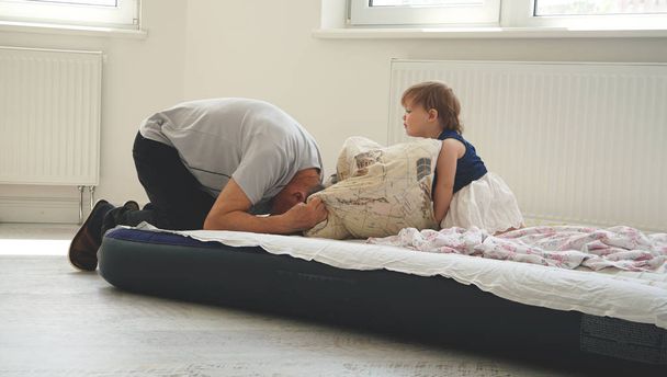 A charming funny little girl sitting in a bed with her farther - Fotoğraf, Görsel