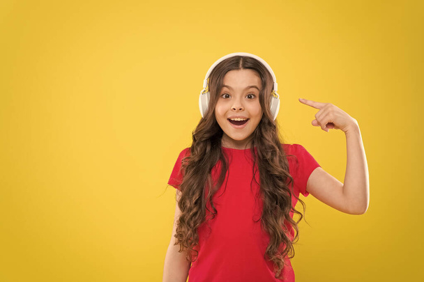 Music to your ears. Adorable child listen to music playing in earphones on yellow background. Little girl enjoying her favorite music. Cute small kid listening to music in headset, copy space - Foto, afbeelding