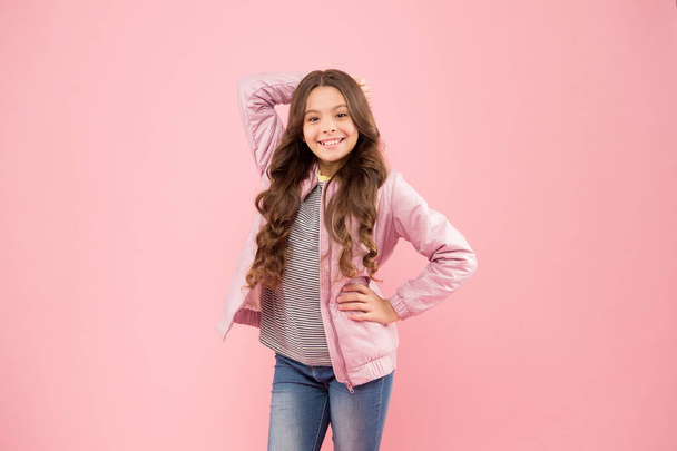 Long and curly. Happy small girl with long hairstyle in autumn style. Adorable little child smiling long brunette hair on pink background. Styling long hair for fall season - Fotó, kép