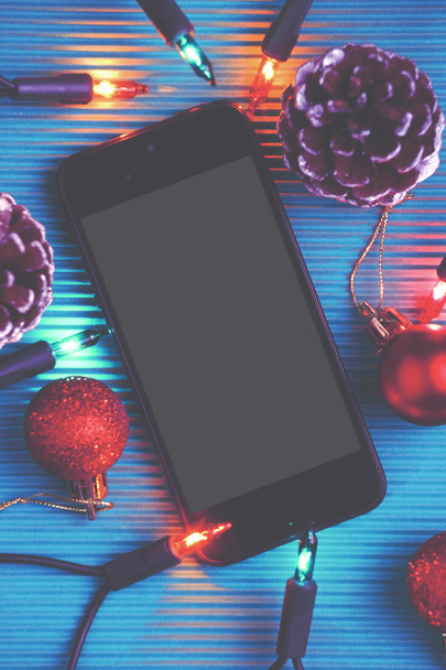 Smart phone and christmas decoration over blue background. - Foto, afbeelding