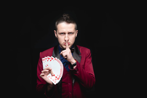 Magician shows trick with playing same cards on dark background. Disclosure of focus - Photo, Image