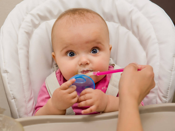 Mother feeding her baby girl with a spoon.  - 写真・画像