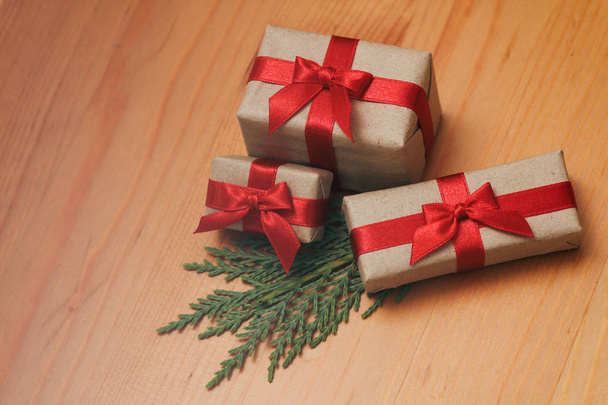 Some gift boxes wrapped in brown craft paper and tie red satin ribbon. Decorative wooden background. Your text space. Set of presents. - Fotografie, Obrázek