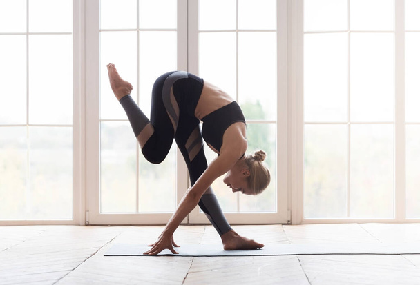 junge Yoga-Frau berührt ihr Knie mit der Stirn - Foto, Bild