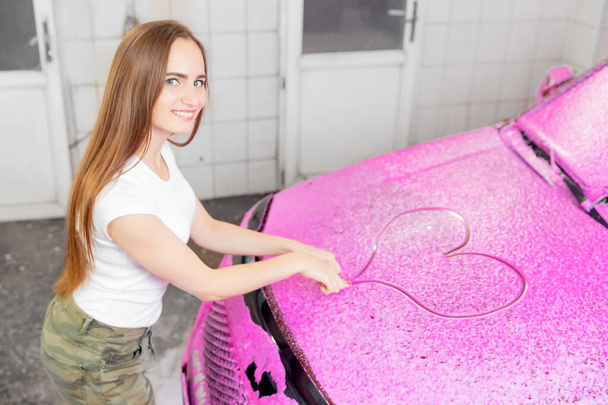 Araba yıkama servisi, kir temizlemek için eko pembe köpüğe kalp çiziyor - Fotoğraf, Görsel
