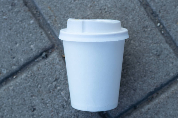 a white paper cup with a lid lies on the city road to the cities of Dnieper - Fotografie, Obrázek