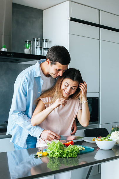 Man kissing girlfriend while she preparing breakfast in kitchen - Foto, immagini