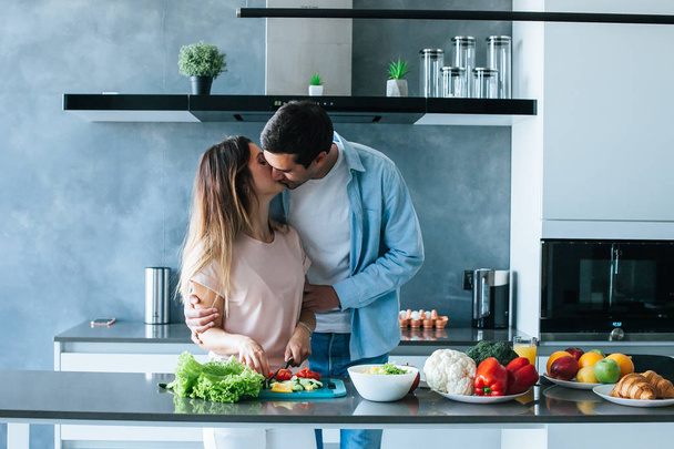 Happy young couple embracing during breakfast in kitchen - Φωτογραφία, εικόνα