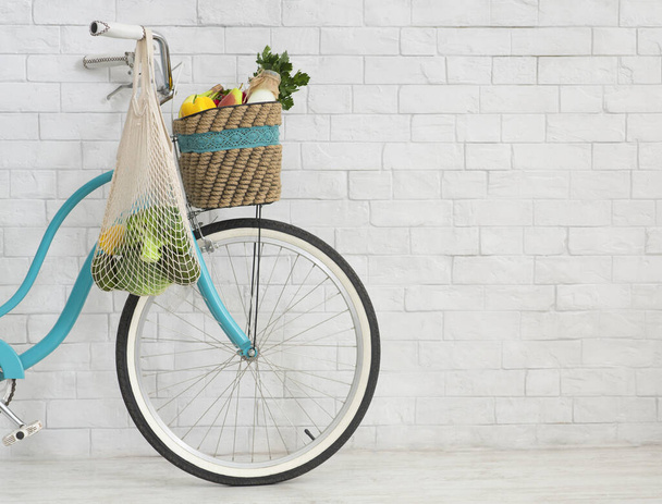 Bicicleta ecológica con bolsa de compras neta llena de comida vegetariana
 - Foto, Imagen