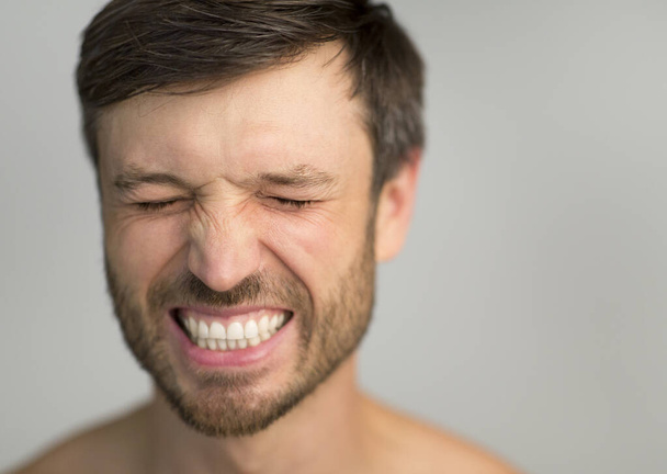 Muž se zavřenýma očima Usmívající se přes šedé studio na pozadí - Fotografie, Obrázek