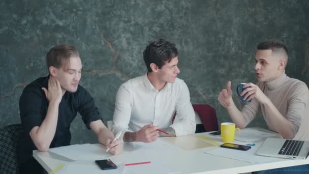 Kollegat hauskaa puhua tauon aikana toimistossa. kolme nuorta miestä juo kahvia ja juttelee
 - Materiaali, video
