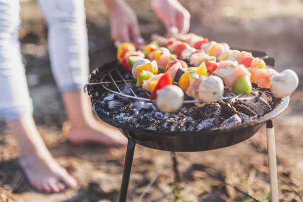 Close up of young female preparing mixed vegetable and chicken meat skewers on barbecue grill outdoors. - Foto, Bild