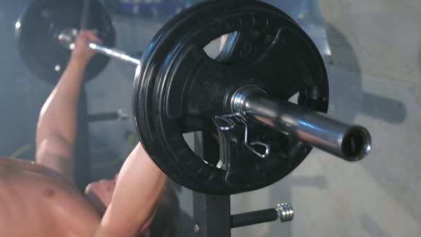 Athletic man bodybuilder doing barbell chest exercise on bench, closeup view. - Séquence, vidéo