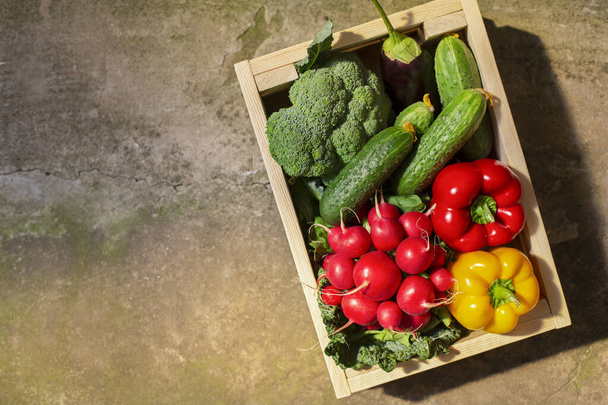 Овощи, полные витаминов в эко деревянной коробке на бетонном полу
 - Фото, изображение