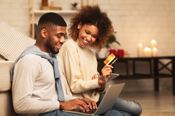 ラップトップを見てオンラインで購入する幸せなアフリカ系アメリカ人のカップル - 写真・画像