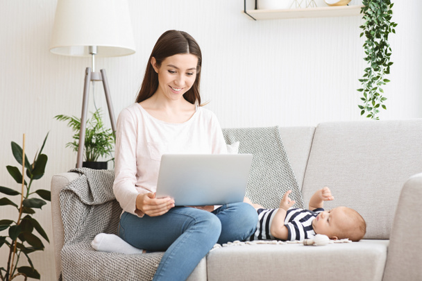 Όμορφη νεαρή μητέρα ανάγνωση μωρό blog στο laptop - Φωτογραφία, εικόνα
