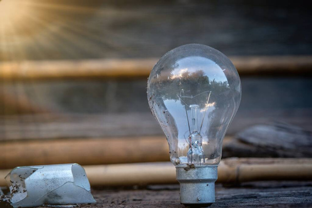 Lâmpada de pé sobre madeira com luz solar - Conceito de poupança de energia e tem uma grande ideia
. - Foto, Imagem