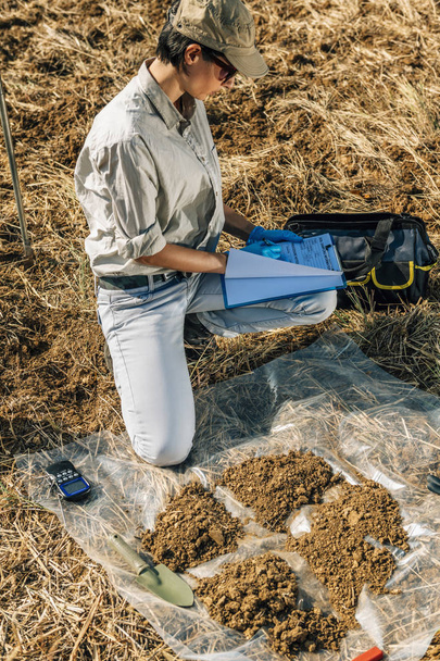 Prueba de suelo. Mujer agrónoma tomando notas en el campo. Protección del medio ambiente, certificación del suelo orgánico, investigación
 - Foto, Imagen