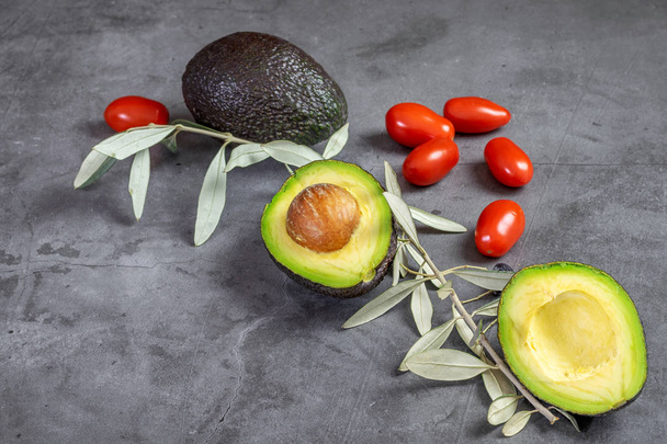 Fresh ripe avocado with little tomatoes cherry on the black background. - Photo, Image