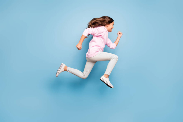 Full length body size photo of cheerful side profile positive crazy excited casual preteen wearing pink pants trousers footwear hurrying for discount isolated over pastel blue color background - Фото, зображення