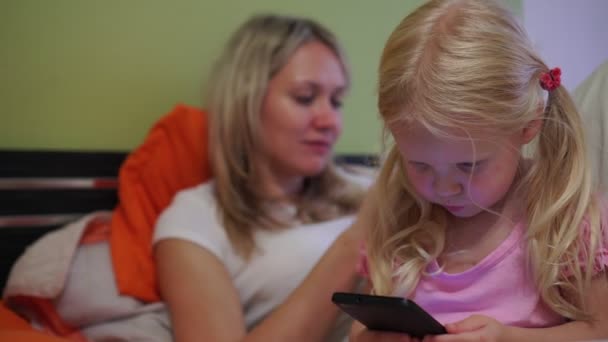 Eine moderne Familie nutzt Smartphones. Mutter mit Tochter mit Handy. - Filmmaterial, Video
