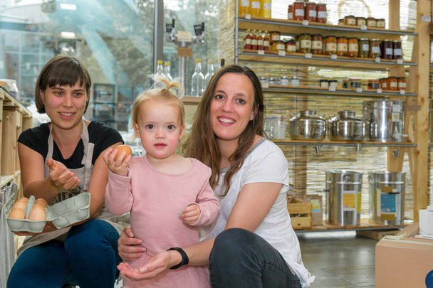 Mother and daughter picking some fresh eggs in zero waste store. - Foto, Bild