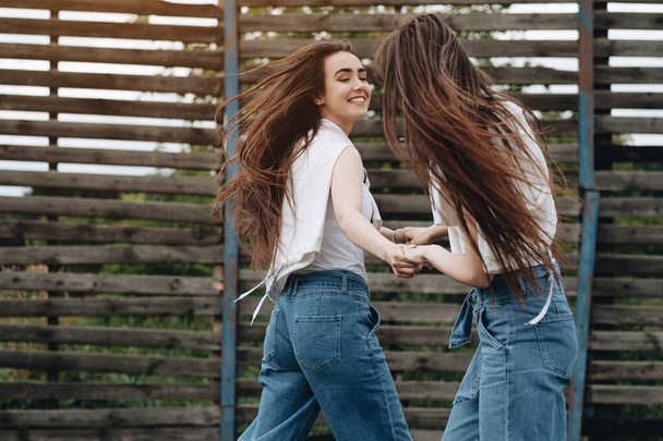 Retrato de duas jovens gêmeas morena irmãs vestidas de jeans e camiseta branca, Melhores amigos sempre conceito
 - Foto, Imagem