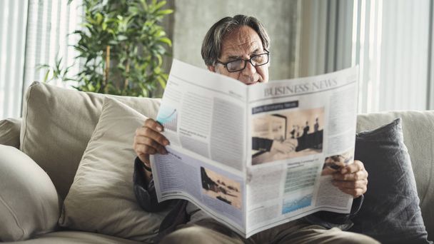 老人は家で新聞を読んでいる - 写真・画像